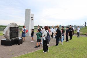 公園内の想いの丘にある震災モニュメント前で説明を受ける参加者ら