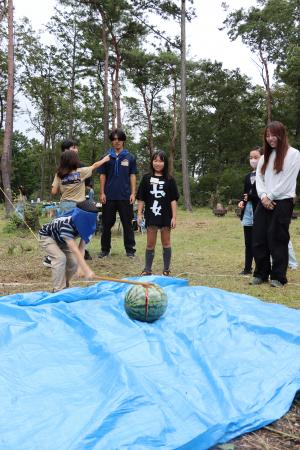 すいか割りをする学生と児童